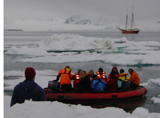 Passagiere des Cape Farewell kehren mit dem Zodiac nach einem Mitternachtspaziergang in Svalbard zum Schiff zurück